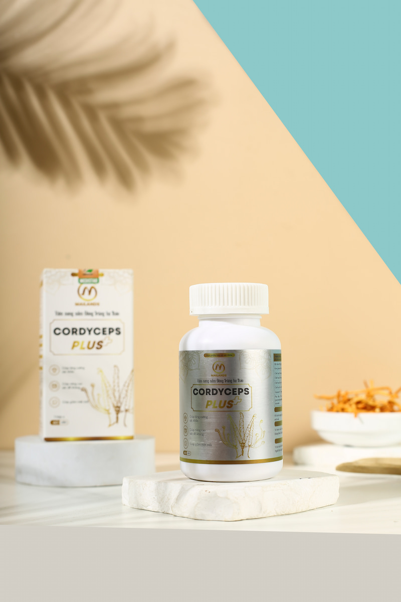 Một hộp thuốc đông trùng hạ thảo và một chiếc thìa đặt cạnh bát chứa sợ nấm đông trùng hạ thảo có dán nhãn 'Viên nang đông trùng hạ thảo cordyceps Plus'